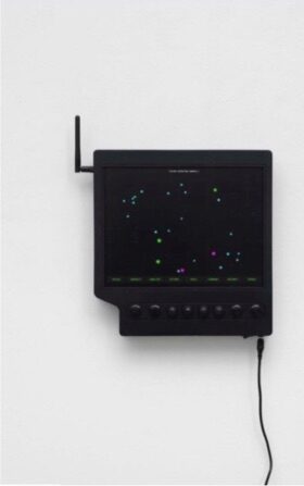 A wall-mounted black interface with an antenna, its dark screen scattered with small coloured points.